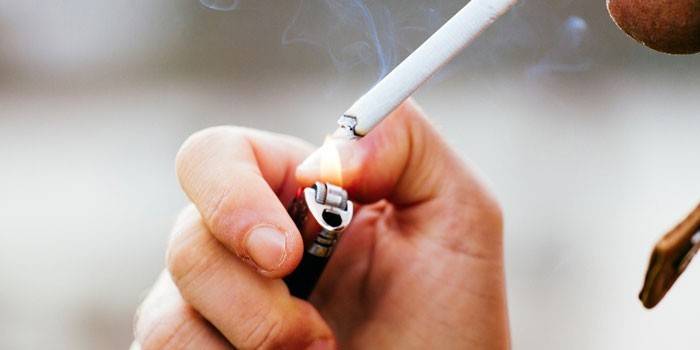 Un hombre enciende un cigarrillo desde un encendedor