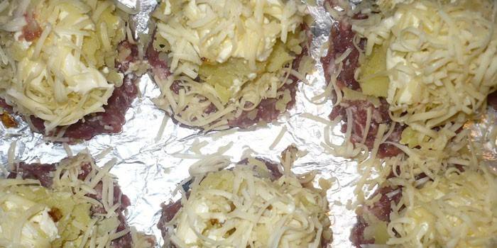 Pilhas de carne picada com batatas em uma folha no forno