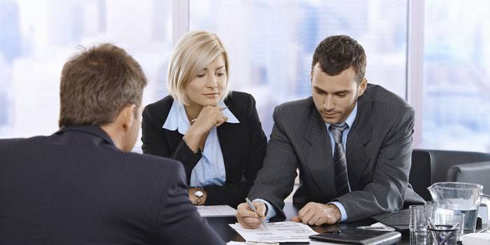 Dois homens e uma mulher em negociações comerciais