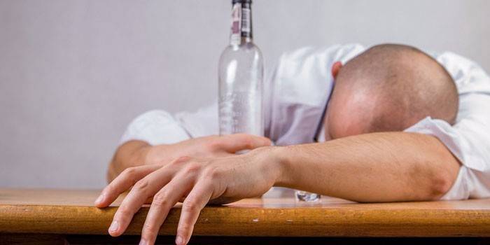 Hombre durmiendo en la mesa con una botella