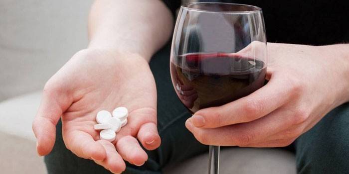 Vinho em um copo e pílulas na palma da sua mão