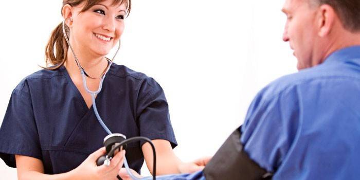 O médico mede a pressão do paciente