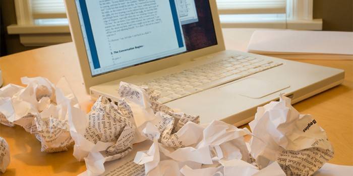 Zmięte arkusze z tekstami na tle notebooka