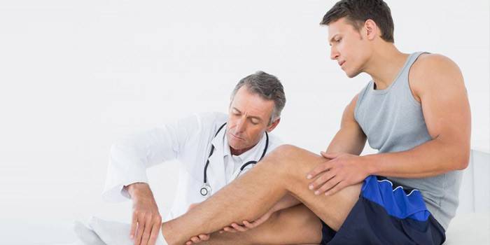 O médico examina a perna do paciente