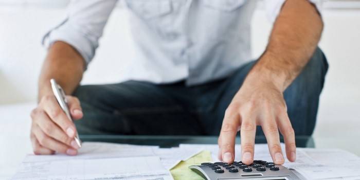 Um homem faz cálculos usando uma calculadora