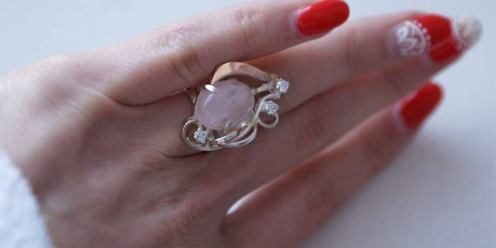 Anillo de oro con cuarzo rosa en mano de mujer.
