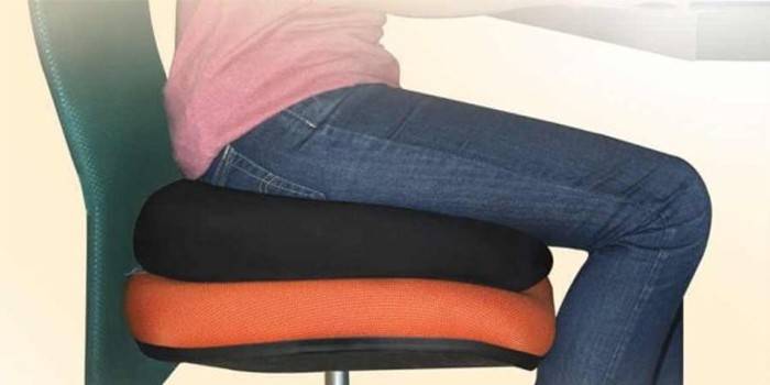 Un hombre se sienta sobre una almohada de hemorroides