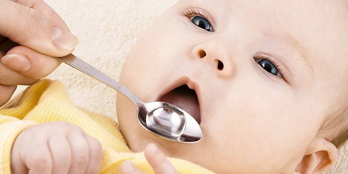 Al niño se le da un medicamento en una cuchara.