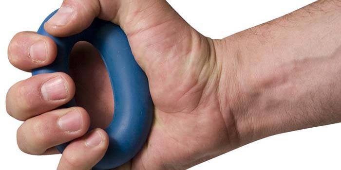 Mão masculina aperta o expansor do carpo