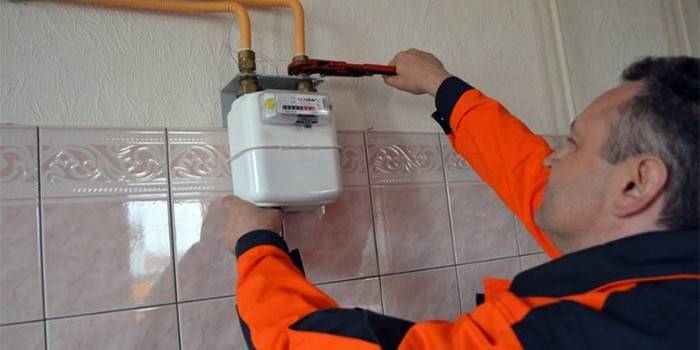 El maestro instala un medidor de gas en la habitación.