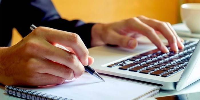 Mężczyzna przy laptopie z długopisem w ręku