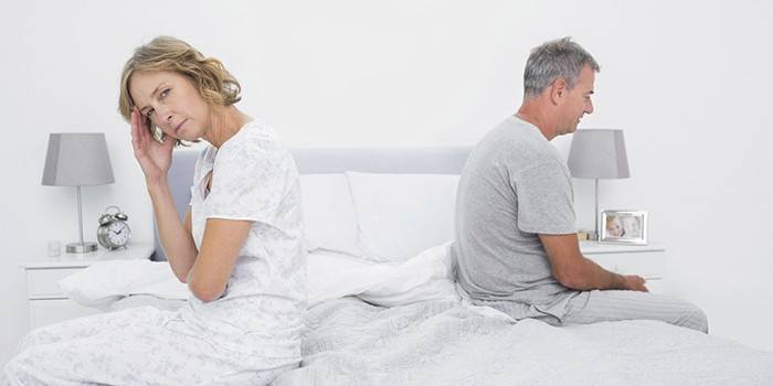 Hombre y mujer están sentados en la cama.