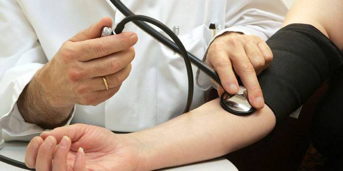 El doctor mide la presión de una mujer.