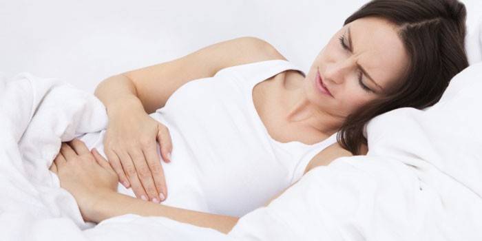 A mulher gravida prende a barriga com as duas mãos.