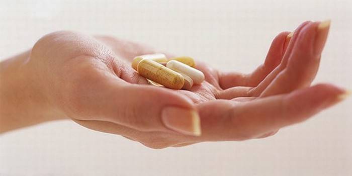 Pastillas y cápsulas en la palma de su mano.