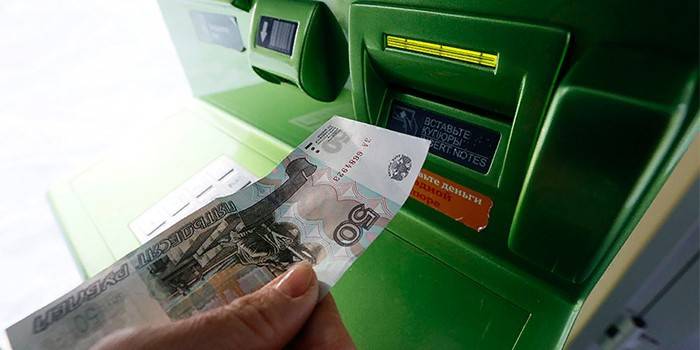 Kobieta z rachunkiem w ręku w pobliżu bankomatu