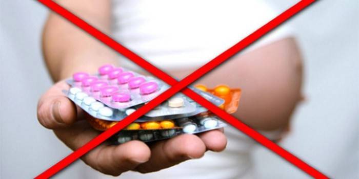 Imagen cruzada de mujer embarazada con pastillas en la mano