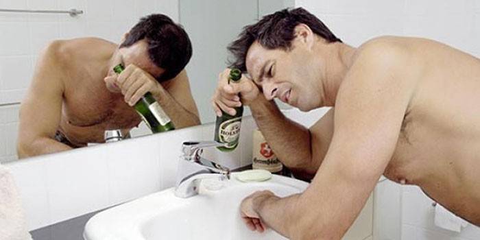Hombre en el baño con una botella de cerveza.
