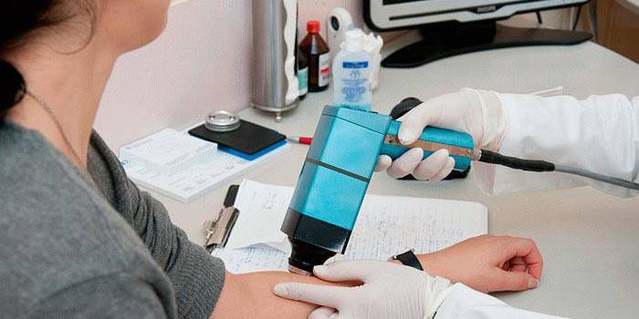 O médico realiza uma dermatoscopia epiluminescente da pele do paciente