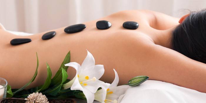 Menina no procedimento de spa com pedras quentes
