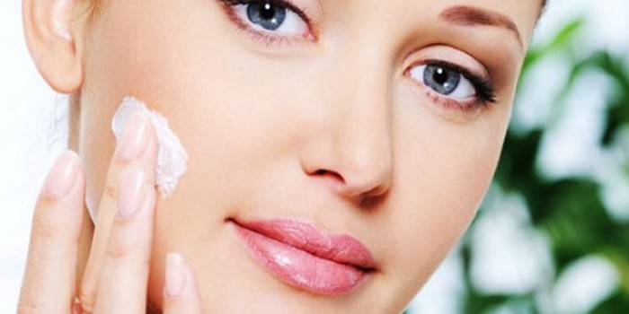 Chica pone crema en su cara