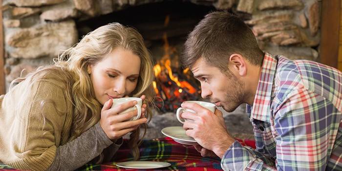 El chico y la chica están bebiendo té cerca de la chimenea.