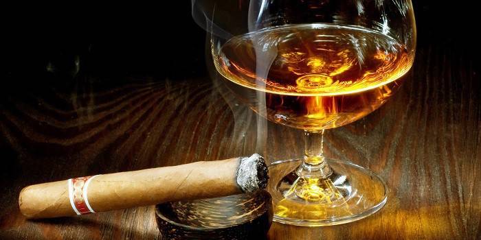 Tlące się cygaro i kieliszek alkoholu