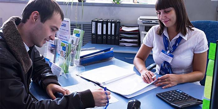 Um homem assina documentos em um banco