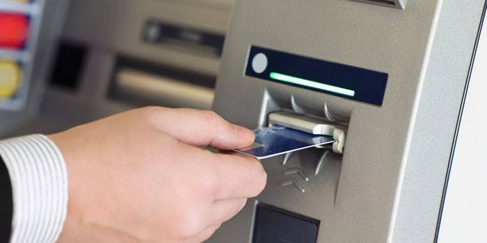Mężczyzna wkłada kartę do bankomatu