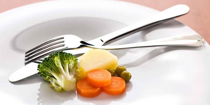 Prato com uma pequena porção de legumes e talheres