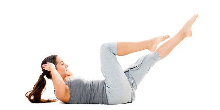La niña realiza una bicicleta estática para los abdominales.
