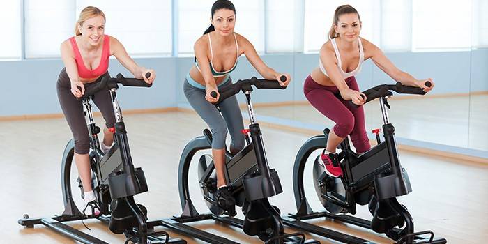Três meninas em bicicletas de exercício