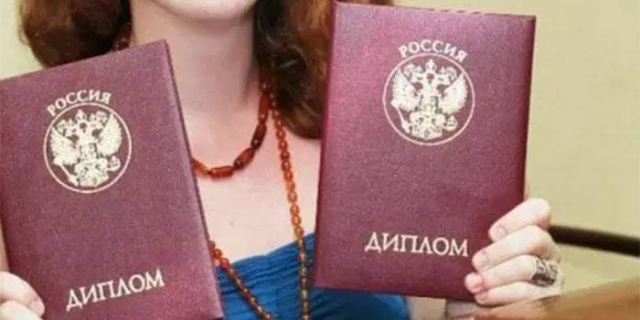 Uma menina com dois diplomas nas mãos dela