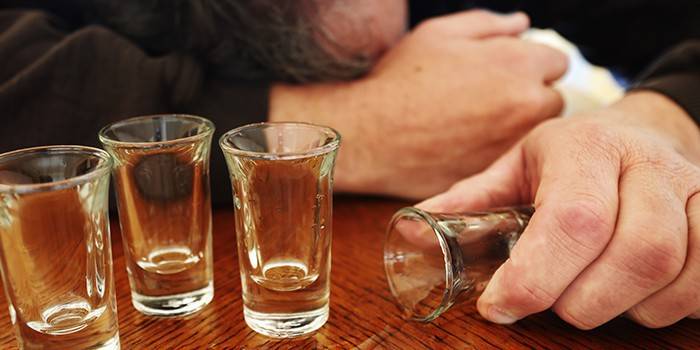 Vasos vacíos y un hombre durmiendo en la mesa