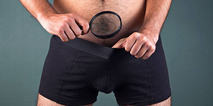 Un hombre con una lupa mira sus calzoncillos