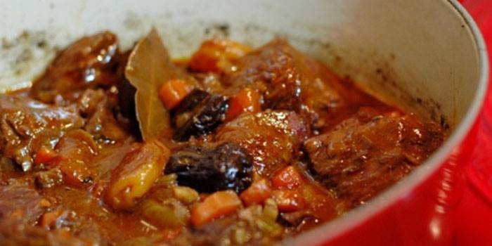 Carne cozida em um caldeirão com ameixas