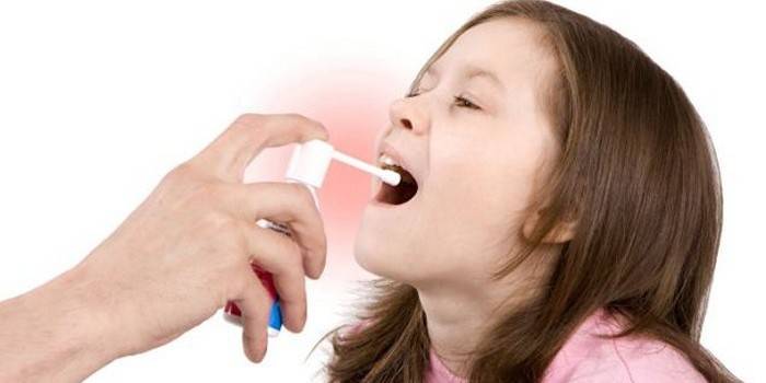 A menina é tratada com uma garganta de spray