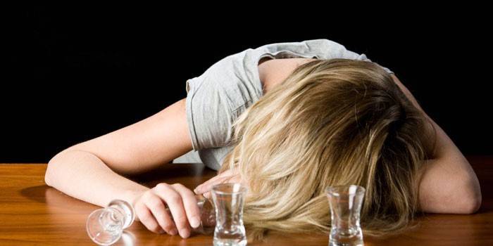 Niña durmiendo en la mesa y vasos vacíos