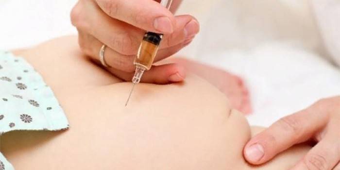 El médico inyecta al niño en la nalga.
