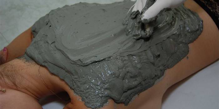 Colocando argila azul nas costas de uma menina