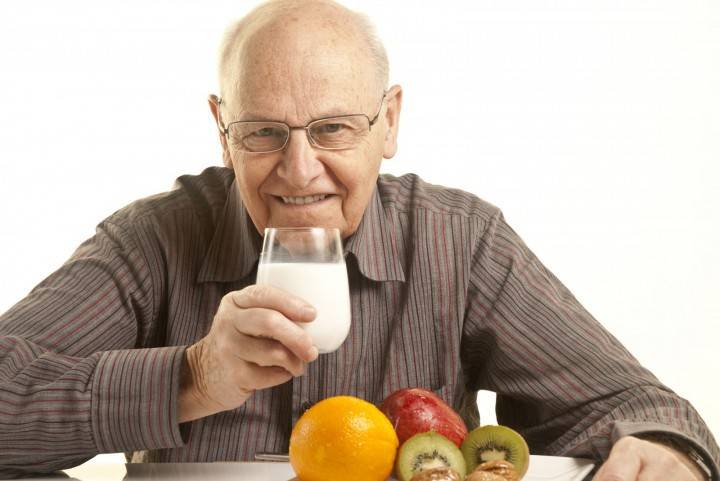 Anciano con un vaso de kéfir y frutas