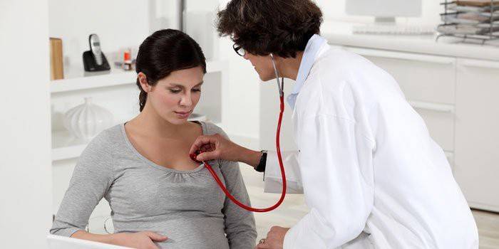 Médico ouve os pulmões de uma mulher grávida