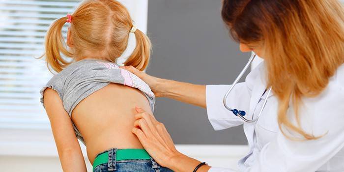 O médico examina a espinha de uma menina