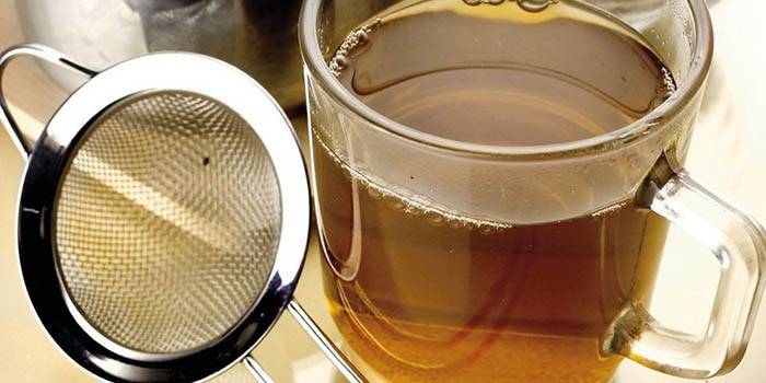 Caldo colado en una taza y colador