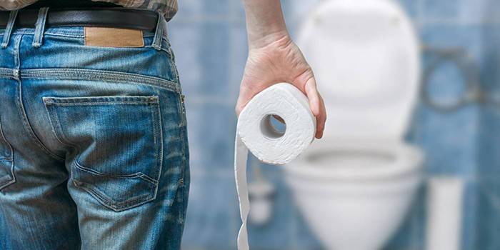 Un hombre con papel higiénico en la mano en el fondo del inodoro.