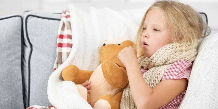 La niña yace en la cama y tose