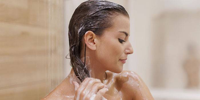Una mujer se lava la cabeza en la ducha