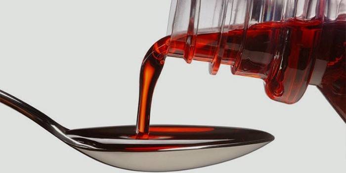 El jarabe se vierte de una botella en una cuchara