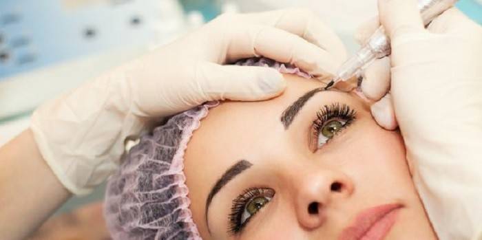 A garota está fazendo biotattoo sobrancelha