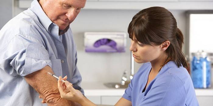 Medic faz uma injeção na mão de um homem